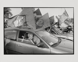 Old woman in car holding flag, Rome, Italy