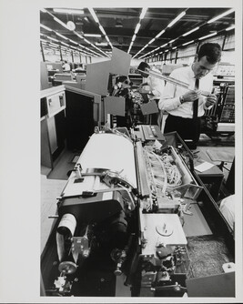 Man inspecting part of machine in IBM factory, Mainz, West Germany