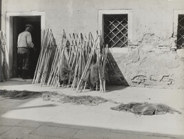 Fishnets in courtyard with man walking into the house, Italy