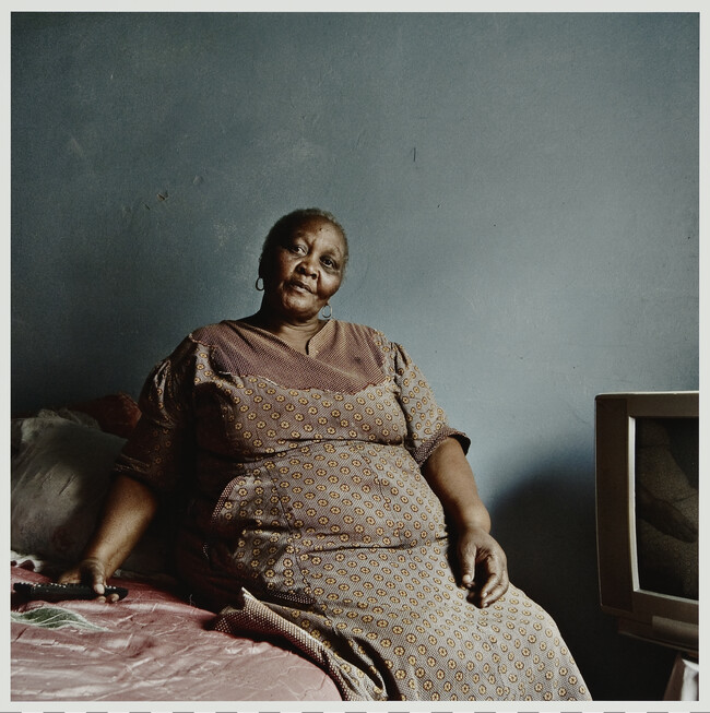 Untitled (Woman seated on a bed near a TV); from The i-jusi Portfolio Number 3: South African Photographs