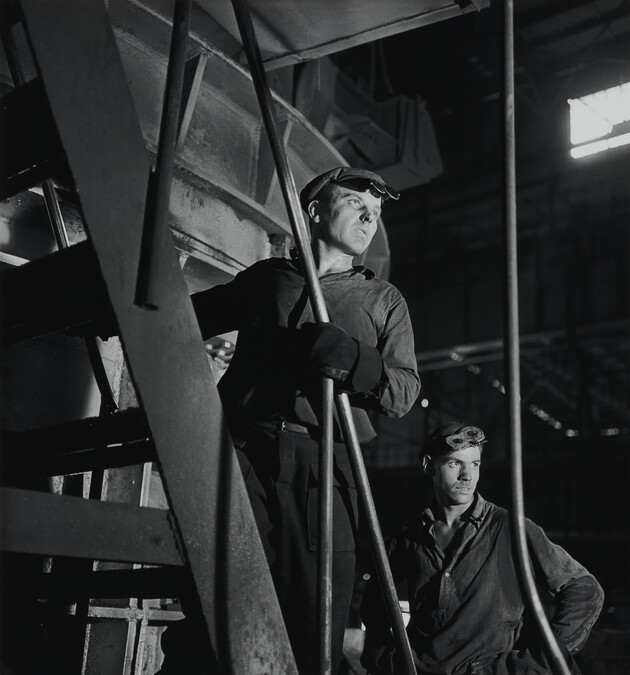 Two factory workers posed on a staircase
