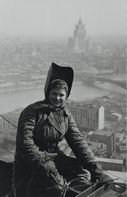 Steeplejack A. Pushkova perched atop a girder of the Hotel Ukraine with a Stalin Building in the background, Moscow