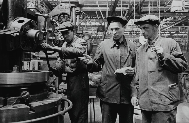 Technical Engineer H. V. Norets (center) explains his innovation to colleague A. M. Ivanov, as machinist V. P. Alekseev looks on, Kirov Tractor Factory, Ural Industrial Complex