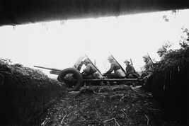 Soldiers advancing with a heavy gun, seen from a trench