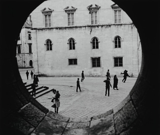 Youths Playing in Town Square Seen Throught Circular Window, Yugoslavia