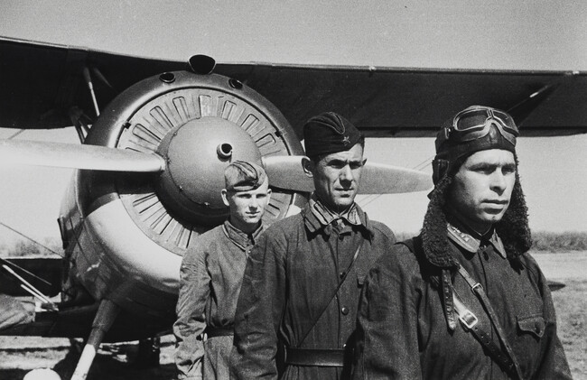 Three airmen posed in front of their aircraft
