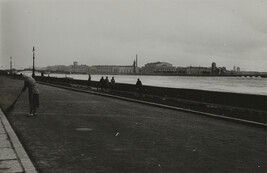 View of woman in scarf sweeping street adjacent to river, Leningrad
