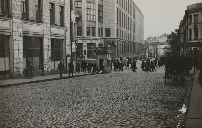 Cobblestone street scene with pedestrians and row of horse-drawn carts, Moscow