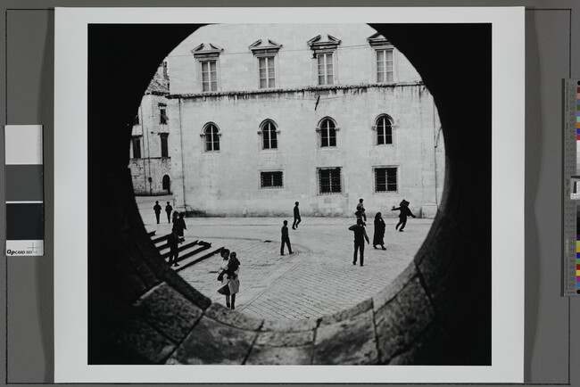 Alternate image #1 of Youths Playing in Town Square Seen Throught Circular Window, Yugoslavia