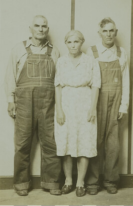 Two Men in Overalls Flanking an Older Woman with a Striped Backdrop