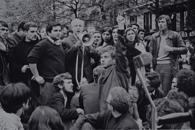 Writer Louis Aragon addressing the crowd through a bullhorn at the Place de la Sorbonne; student leader Daniel Cohn-Bendit with arm raised