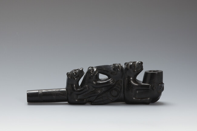 Argillite Pipe depicting a Human Face with Goatee on the Bowl; a Bear holding the Bowl, a Raven and a Frog Facing each Other and another Bear