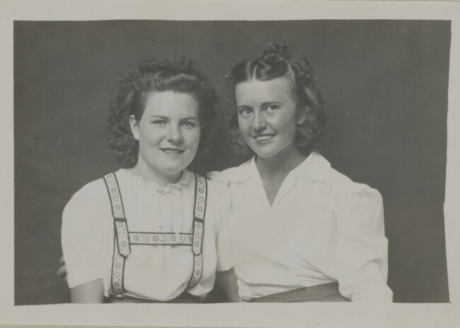 Two Women Wearing White Shirts (one wearing suspenders)