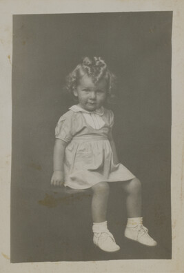 Little Girl in Dress with Yoke Seated on a Table