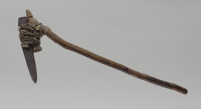 Adze with a heavy iron blade and wooden handle.