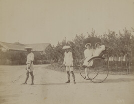 Man standing next to a woman in a rickshaw pulled by two Japanese men. Kamakura, Kanagawa Prefecture,...