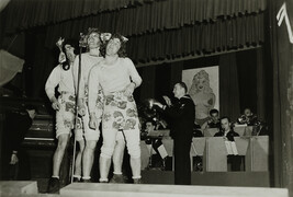 Men Dressed as Women Performing on Stage in Front of Microphone