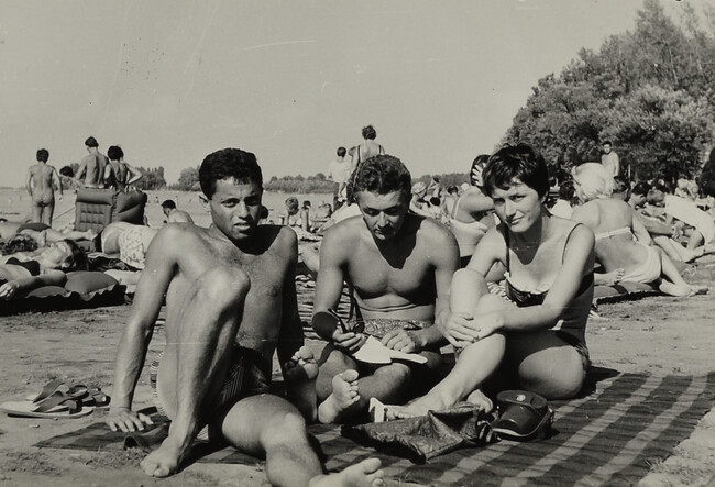 Two Young Men and a Woman Sitting on a Blanket at Beach