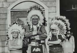 Two Children Flanking a Native American Man, all Wearing Plains-Style Feathered Headdresses