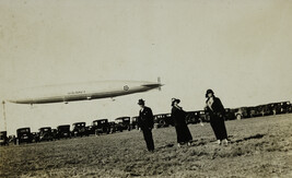 Three People Standing in Field with Blimp and Cars in Background, San Diego, California