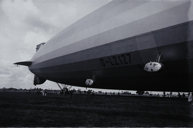 Tail of Blimp Moored to Ground with People in Background