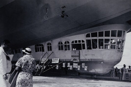 Two People Standing near Passenger Car under Grounded German Blimp