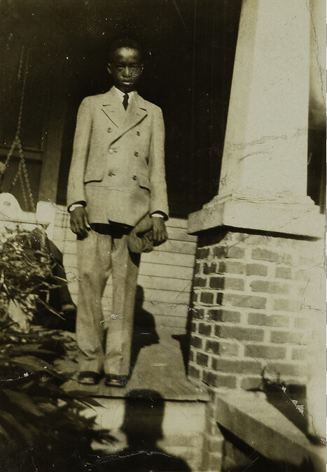 “Doing My Best” [Young Man in Suit Standing on Porch] [from the Photo Album of an African-American Woman]