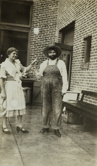 Woman with Woman Dressed in Man’s Overalls and Fake Beard